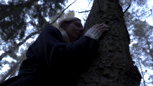 Kobieta przytula się do drzewa.