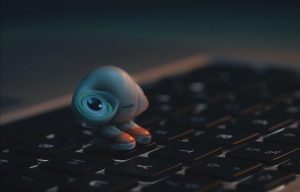 Muszelka z oczami, w trampkach, stoi na klawiaturze laptopa