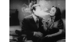 Kobieta i mężczyzna. Kobieta pali i wydmuchuje mężczyźnie w twarz kłęby dymu.