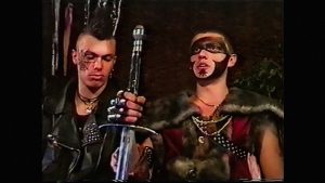 Kadr z filmu. Dwa młodzi mężczyźni, z umalowanymi twarzami w plemienne wzory, z mieczem, w odzieży ze skóry i futra.