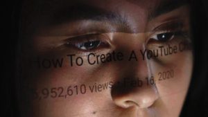 W półmroku, na fragmencie twarzy , pod linią oczu odbija się tekst z ekranu komputera.