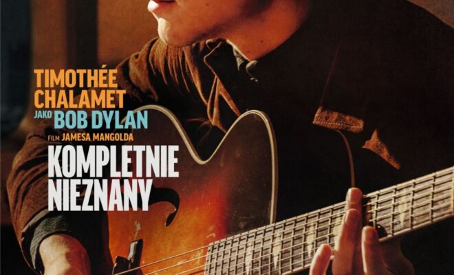 plakat. mężczyzna z bujnymi kręconymi włosami, w ciemnych okularach, gra na gitarze akustycznej