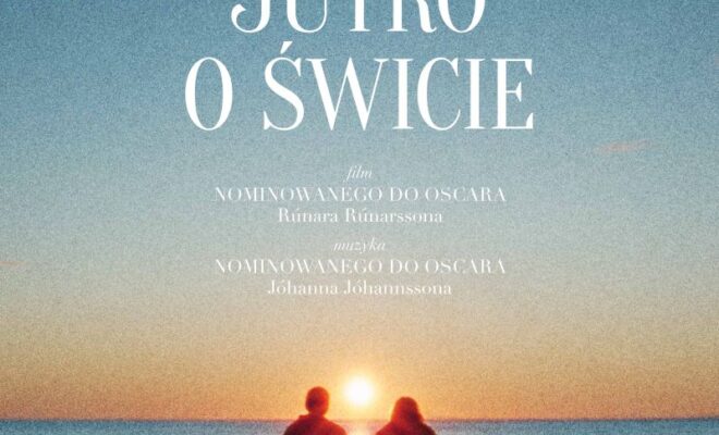 dwie postaci na skale, na tle wody i wschodu słońca