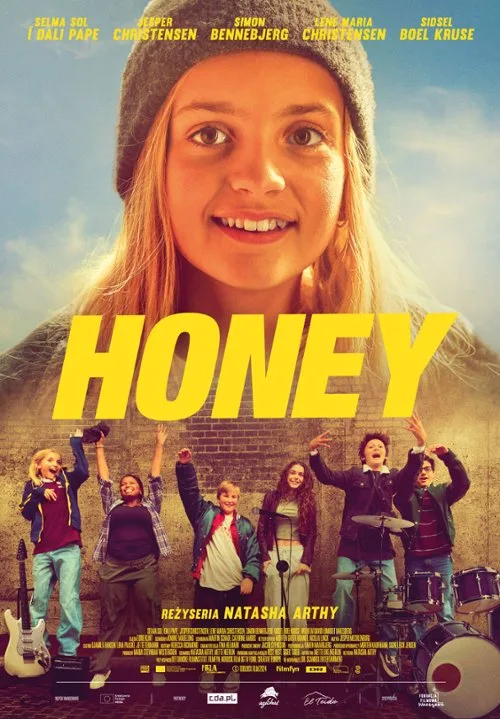uśmiechnięta blondynka w czapce na tle nieba. poniżej 6 innych postaci z filmu, machają rękoma wyciągniętymi w górę