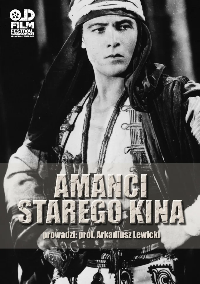 kadr z czarno-białego filmu - młody mężczyzna w kapturze, rozpiętej koszuli, obwieszony ozdobami i bronią