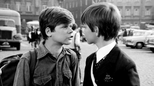 czarno-biały kadr. dwóch chłopców na przeciw siebie, jeden mówi coś do drugiego.