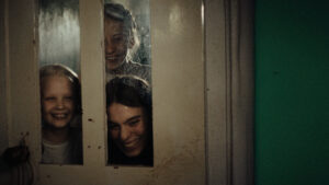 stare, kremowe przeszklone drzwi - za nimi trzy roześmiane dziewczyny.