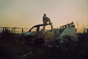 kobieta na wraku auta o zachodzie słońca