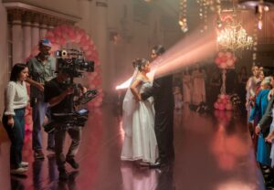 młoda para w świetle reflektorów, obok niej duża kamera i operator kamery