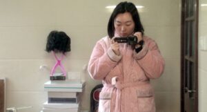 kobieta w różowym szlafroku, z kamerą cyfrową