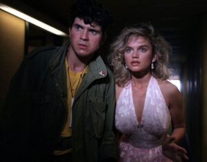 blondynka w białek sukience i mężczyzna w żółtej koszulce i zielonej kurtce patrzą zaniepokojeni przed siebie