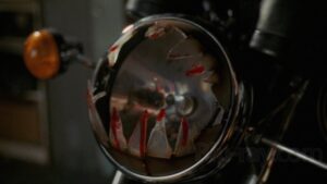 kadr - lampa motocykla pochlapana czymś czerwonym, z doklejonymi zębami